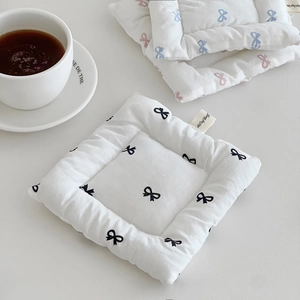 Detailed view of quilted cotton bow coaster with brand tag and thick heat insulation