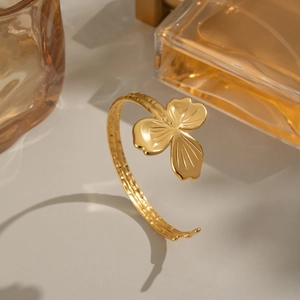Bracelet jonc trèfle plaqué or 18 carats pour femme sur une surface neutre chic
