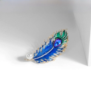Detail of peacock feather brooch with blue enamel, teardrop crystal and white pearl inlay