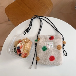 Détail du mini sac en peluche à pois colorés avec une bandoulière en corde rayée