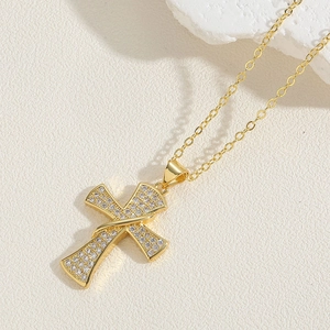 Detailed view of gold cross pendant necklace with micro-paved white zircons on O-chain