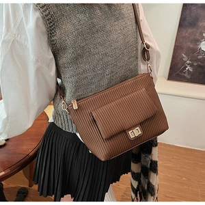 Détail de la texture en cuir plissé marron et du fermoir rotatif en métal doré