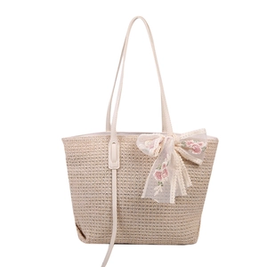 Minimalist beige woven straw tote bag featuring a large lace bow with pink floral embroidery