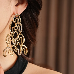 Detailed close-up of golden irregular wave earrings with sparkling diamond pavé inlay