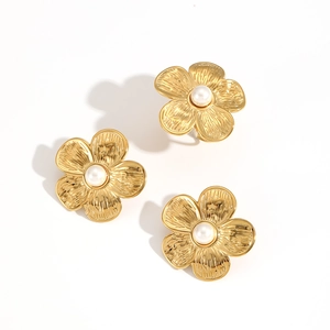 Detailed view of three golden flower earrings featuring white pearls on white background