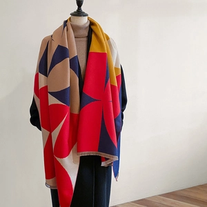 Thick geometric colorblock shawl with tassels styled on a mannequin with a coat