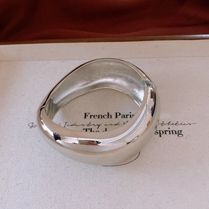 Detailed view of polished wide metal bangle with a sleek hinge and French minimalist design