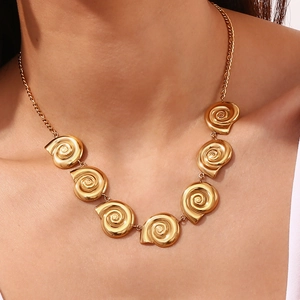 Close-up of 18K gold plated necklace featuring spiral snail shell charms on a model