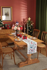 Detail of Christmas table runner with reindeer and snowflake prints on a wooden dining table