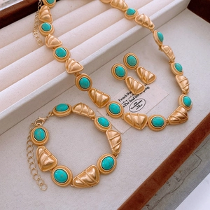 Vintage jewelry set with gold metal and turquoise stones in a beige velvet jewelry box