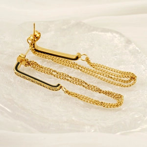 Detailed close-up of gold tassel earrings with three-layer chains and black enamel inlay