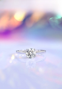 Detailed view of 1-carat moissanite ring with classic prong setting on a reflective base