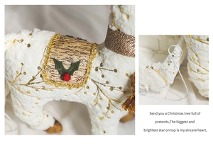 Detail of white plush reindeer Christmas decoration with gold glitter patterns and berries
