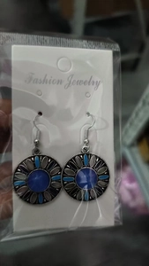 Dettaglio di orecchini boho tondi con pietra blu su cartoncino porta gioielli