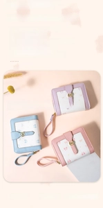 Three bow-patterned short wallets in purple, blue, and pink with golden bow clasps