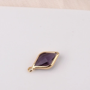 Detailed macro view of a gold-plated rhombus pendant with a purple faceted crystal insert