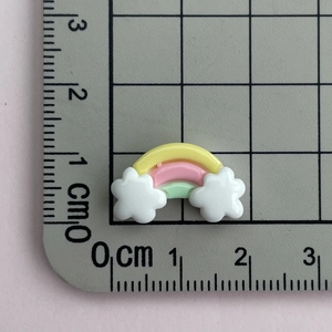 Close-up of a 2cm mini rainbow and cloud resin charm on a metric measurement scale