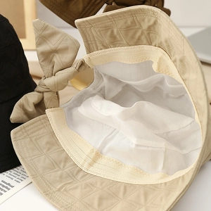 Close-up of beige quilted bucket hat showing white breathable lining and sweatband details