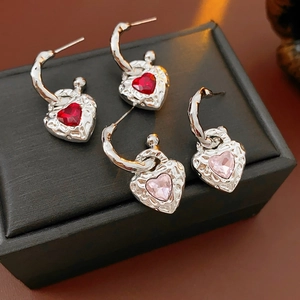 Close-up of vintage heart earrings with red and pink gemstones on a jewelry box