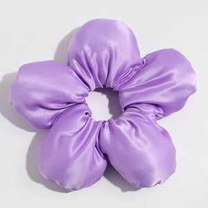 Macro view of purple satin flower hair tie with silky fabric and puffy petal details