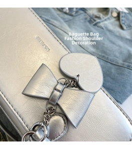 Detail of silver baguette bag featuring a metallic bow charm and NOFILTER logo embossed