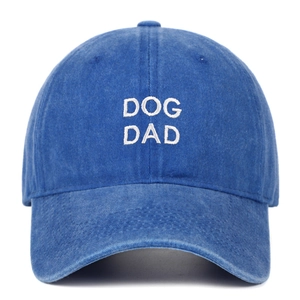 Detailed view of white DOG DAD embroidery on a navy washed cotton baseball cap texture