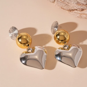 Two-tone heart drop earrings featuring silver heart charms and gold beads on pink background