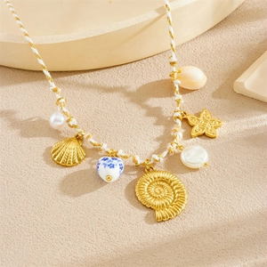 Detailed view of woven necklace with gold starfish, shell charms and ceramic heart bead