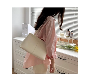 Model wearing a minimalist cream white PU leather tote bag in a bright interior setting