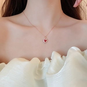 Dettaglio di una collana a cuore in oro rosa con pendente in zircone rosso su modella