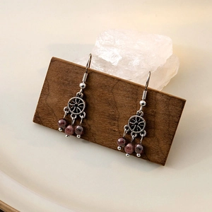 Vintage silver hollow round earrings with bohemian red garnet beads on a wood display