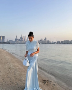 Elegant light blue maxi dress detail showing pleated silk fabric during sunset outdoors