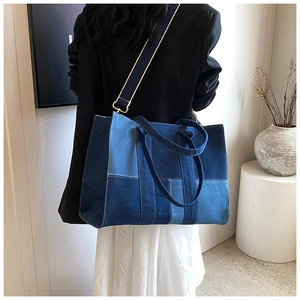 Rear view of model wearing a large patchwork denim tote bag with blue canvas straps
