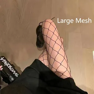 Detail showing large mesh fishnet stockings styled with a black skirt and shoes