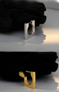 Macro detail of minimalist square silver and gold geometric earring clasps with shadows