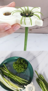 Detail showing the white scallion slicer tool creating fine shreds of green onions