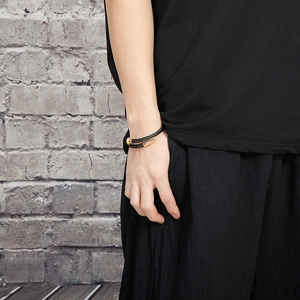 Macro shot of black twisted cable bracelet with polished gold metal ends on wrist