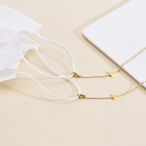 Minimalist gold titanium steel mask chain with a cross pendant for women shown on a mask