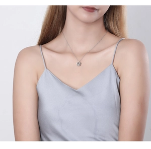 Detailed close-up of a silver crown pendant necklace worn on a woman's collarbone