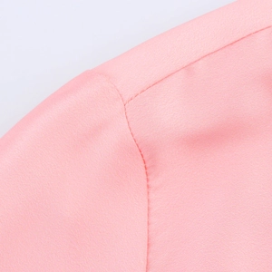 Détail de la texture du tissu et des coutures sur une chemise rose à manches longues fleurie