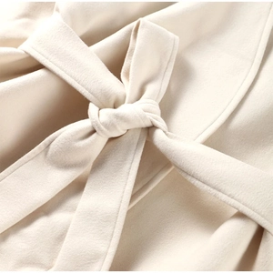 Detailed view of beige wool coat with a focus on the elegant waist tie and fabric texture