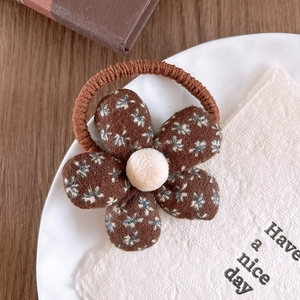 Close-up of floral fabric hair tie with brown petal patterns and a plush center ball