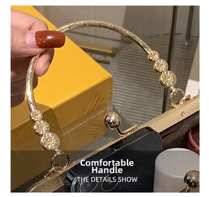 Detail of the golden metal handle with floral motifs on a stylish crossbody bag