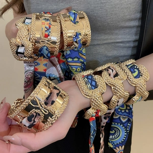 Detail showing gold cuffs with silk scarves including leopard and geometric patterns