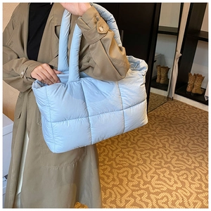 Close-up of light blue quilted puffer tote bag with soft padded texture for autumn