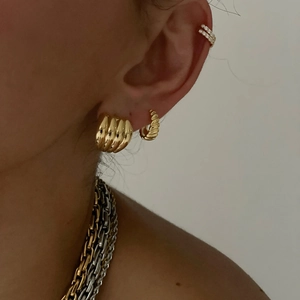 Detailed close-up of 18k gold croissant earrings and layered chain necklace on model