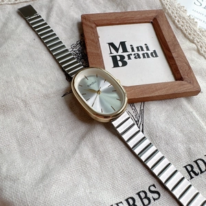 Detailed macro shot of vintage oval quartz watch with gold metal link band on linen