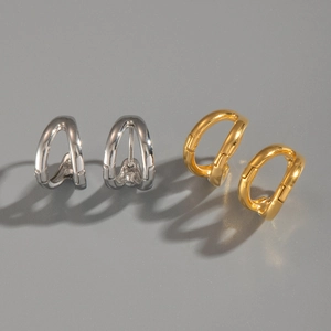 Macro detail of double C-shape 18k gold and silver earrings with polished mirror finish
