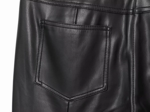 Detailed macro view of black faux leather pants featuring rear pockets and reinforced stitching
