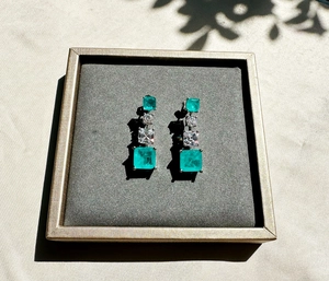 Macro detail of 925 silver emerald earrings with four square emerald and crystal stones